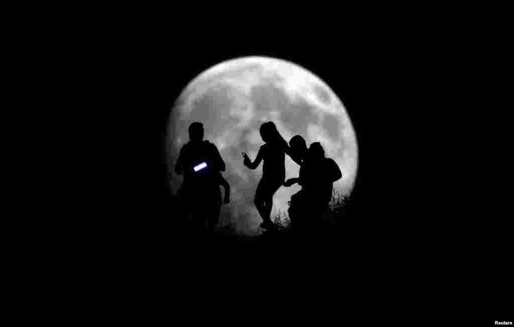 A group of hikers are silhouetted against the moon in Tijuana, Mexico, Aug. 27, 2015.