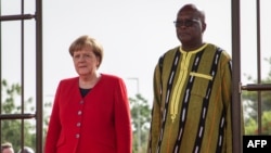 La chancelière allemande Angela Merkel (à gauche) aux côtés du président du Burkina Faso, Roch Marc Christian Kabore (à droite) lors d'une cérémonie de bienvenue au palais présidentiel de Ouagadougou le 1er mai 2019.