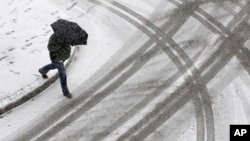 A man crosses the street as a light snow falls in Baltimore, Maryland, Jan. 21, 2014. 