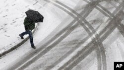 A man crosses the street as a light snow falls in Baltimore, Maryland, Jan. 21, 2014. 