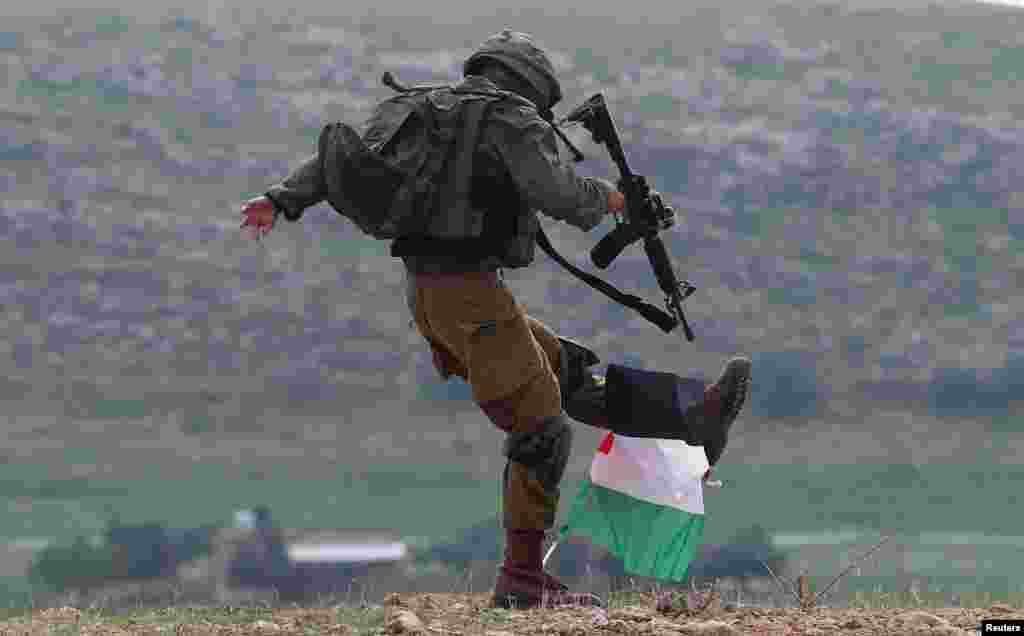 An Israeli soldier kicks a Palestinian flag during a protest against the U.S. president Donald Trump&rsquo;s Middle East peace plan, in Jordan Valley in the Israeli-occupied West Bank.