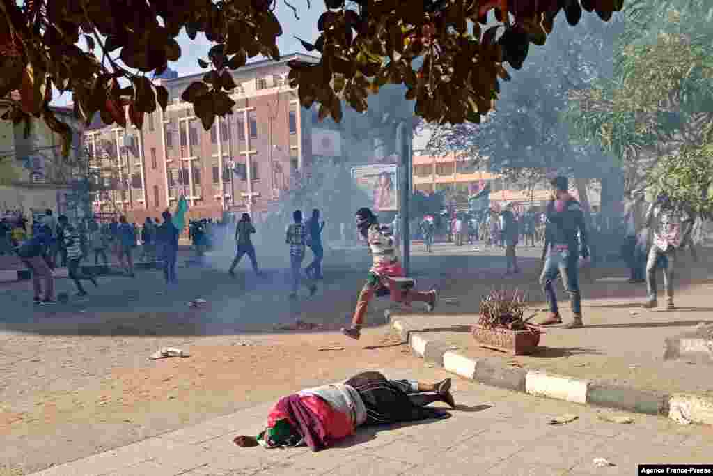 A wounded Sudanese protester falls on the pavement after security forces fired tear gas during a rally to mark three years since the start of mass demonstrations that led to the ouster of strongman Omar al-Bashir, in the capital Khartoum.