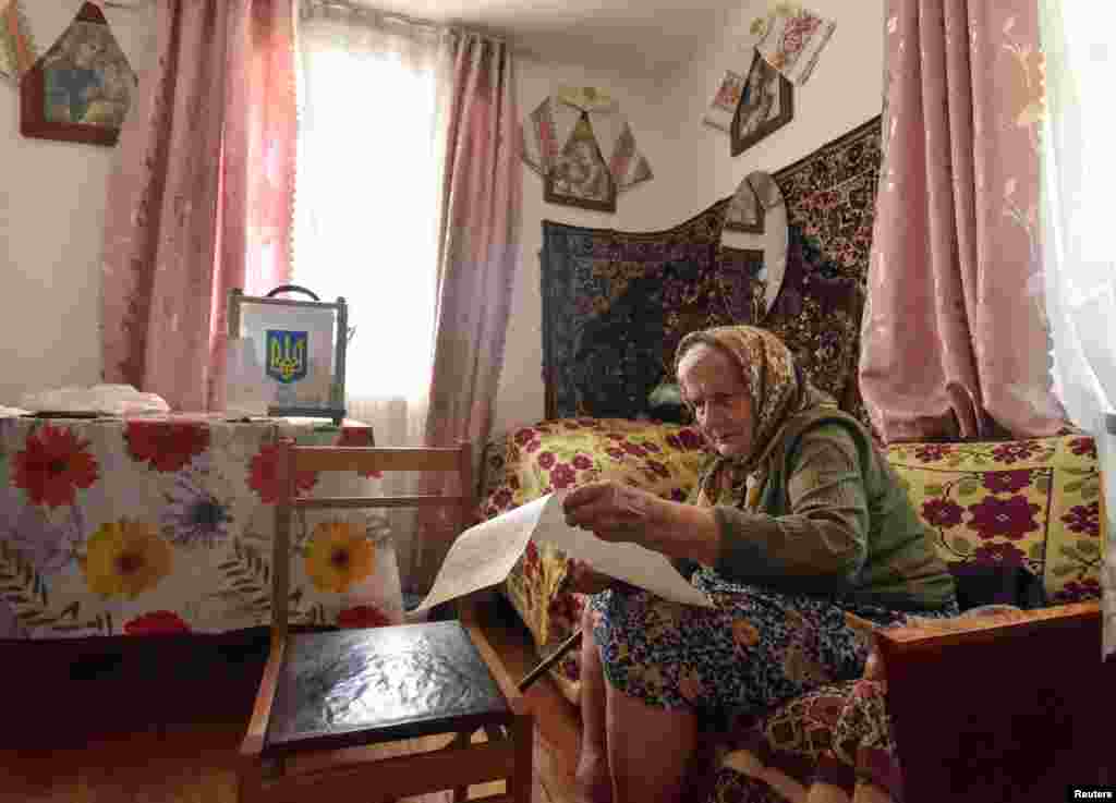 A local resident studies her ballot at home during a parliamentary election in the village of Krekhiv in Lviv region, Ukraine.