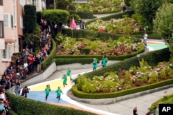 FILE - In this Aug. 19, 2009 file photo, children run down Lombard Street in San Francisco, transformed for the day into a gigantic Candy Land board game to commemorate the game's 60th anniversary. Tourists may soon have to pay a fee to drive down the street.