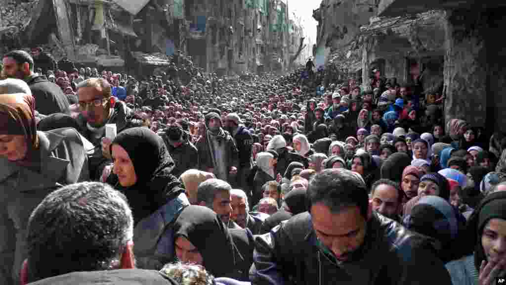 31 janvier 2014 (UNRWA) des&nbsp;résidents du camp palestinien assiégé de Yarmouk font la queue pour recevoir des vivres, à Damas, en Syrie.Cette photo prise le 31 janvier 2014.
