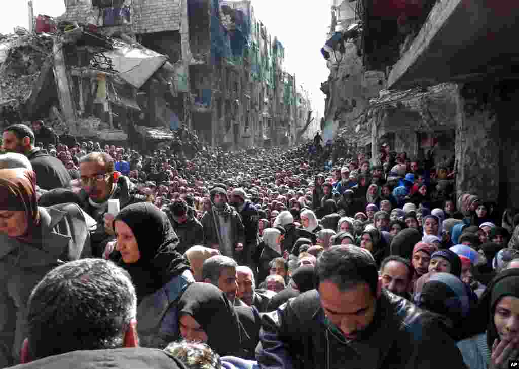 This picture, released by the UNRWA, shows residents of the Palestinian camp of Yarmouk, lining up to receive food supplies, in Damascus, Syria, Jan. 31, 2014.