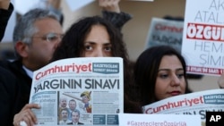 Demonstrators hold placards and copies of the Cumhuriyet daily newspaper as they stage a protest outside a court where the trial of about a dozen employees of the newspaper on charges of aiding terror groups, continues in Istanbul, Oct. 31, 2017.