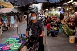 Seorang vendor mengenakan masker di tengah pandemi COVID-19, melewati pasar bunga di Manila, Filipina, 12 Maret 2021. (REUTERS / Eloisa Lopez)