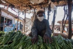 FILE - A vegetable vendor displays his goods inside the Area 23 agricultural commodity market in Lilongwe, Malawi, May 4, 2020.