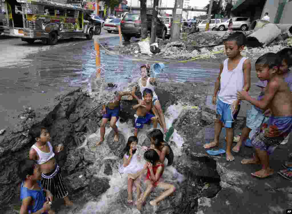 Children take advantage of a busted water pipe which was damaged overnight by a construction company as they take a bath at suburban Quezon city northeast of Manila, Philippines.