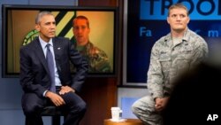 President Barack Obama, accompanied by Tech Sgt. Nathan Parry, takes a question from a service member in Afghanistan, on screen at center, during a town hall with service members at Fort Meade, Md., Sept. 11, 2015.