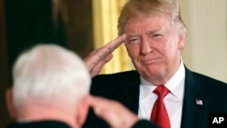 President Donald Trump, right, salutes retired Army Capt. Gary M. Rose, left, before bestowing him with the nation's highest military honor, the Medal of Honor, during a ceremony in the East Room of the White House, Oct. 23, 2017.