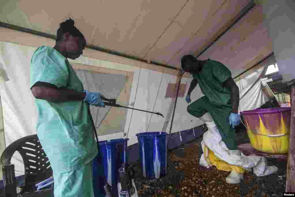 Syerra-Leonedagi klinikalardan birida Ebola bilan kasallangan bemorlarga xizmat ko&#39;rsatgan xodimlar maxsus himoya kiyimlarini yechmoqda, 20-iyul, 2014-yil.