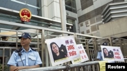 A policeman stands guard next to portraits of Chinese journalist Gao Yu during a demonstration calling for Gao's release from a prison in China, outside the Chinese liaison office in Hong Kong, April 17, 2015.