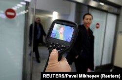 Kazakhstan, Almaty, Kazakh sanitary-epidemiological service worker uses a thermal scanner to detect travellers from China