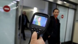 Kazakhstan, Almaty, Kazakh sanitary-epidemiological service worker uses a thermal scanner to detect travellers from China