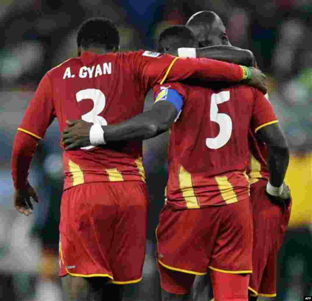 Ghana's John Mensah, center, is comforted by Ghana's Asamoah Gyan, left, after missing a penalty kick during the shootout of the World Cup quarterfinal soccer match between Uruguay and Ghana at Soccer City in Johannesburg, South Africa, Friday, July 2, 2