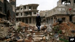 Sumaya Bairuty, 38, an English-language teacher who works in the capital Damascus, walks to her parents house in the war-damaged Bab Dreib neighborhood of Homs, Syria, Jan. 17, 2018. (AP Photo/Hassan Ammar)