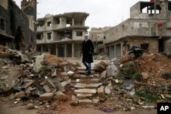 Sumaya Bairuty, 38, an English-language teacher who works in the capital Damascus, walks to her parents house in the war-damaged Bab Dreib neighborhood of Homs, Syria, Jan. 17, 2018.