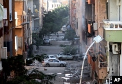 FILE - Damage is seen after clashes between the Libyan military and Islamic militias in Benghazi, Libya, Oct. 29, 2014. Investigators allege armed groups allied with Libya’s two competing governments, multiple independent groups, and Islamic State militants are guilty of wide-ranging abuses.