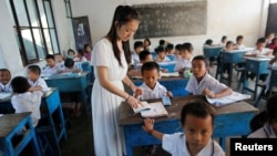 FILE - A teacher teaches Chinese language to kids in a school at Namtit, Wa territory in northeast Myanmar, Nov. 30, 2016.