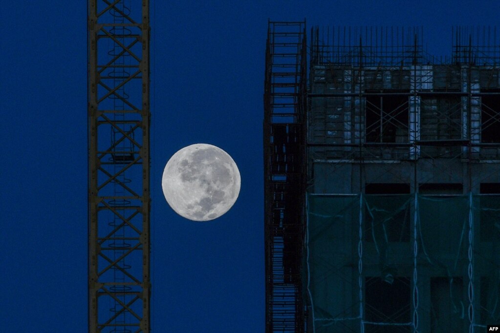 The moon is seen near a building site in Kuala Lumpur.