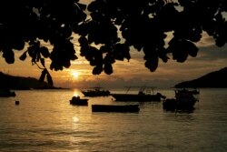 Matahari terbenam di atas teluk kecil dengan memancing dan memancing di jangkar, di Pulau Mahe, Seychelles, 1 Maret 2019. (Foto: AP/David Keyton)