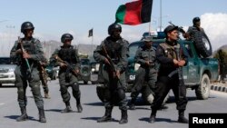 Afghan policemen stand guard near the site of an attack in Kabul, March 25, 2014. 