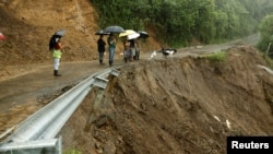 Residents look ta road partially collapsed by heavy rains of Tropical Storm Nate in El Llano de Alajuelita, Costa Rica, Oct. 5, 2017. 