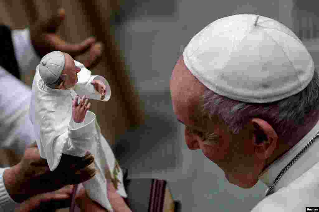 Pope Francis looks at a figurine depicting him held by a woman during the weekly general audience at the Vatican, Feb. 2, 2022.