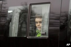 A boy looks through a bus window alleged to be carrying Russian diplomats and their family members who were ordered to leave the US, as they depart from Vnukovo 2 government airport, outside Moscow, Russia, April 1, 2018.