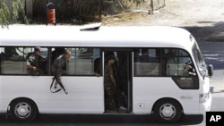 In this citizen journalism image, Syrian security forces lean out of a bus windows as they withdraw from the Damascus suburb of Saqba, Syria, following a campaign of raids and arrests that are part of a nationwide crackdown against protesters calling for
