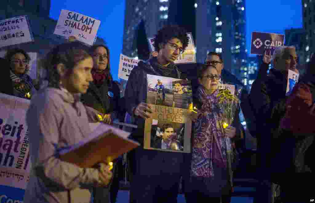 Bahij Chancey, center, holds a photo of his friend and, one of the victims Nicholas Cleves, during an interfaith vigil for peace at Foley Square in response to the Manhattan truck attack, Nov. 1, 2017, in New York.