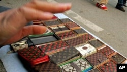 A vendor tries to prevent photographs being taken of fake Louis Vuitton and Coach brand purses she was selling on a street in Beijing. 