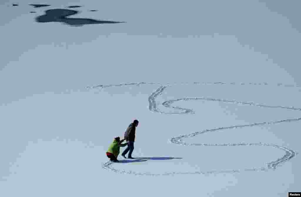 دو نفر در حال بازی روی آب یخ بستۀ یک دریا در ولایت لویننگ چین.