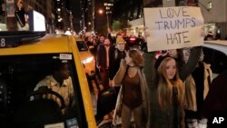 Demonstran melambai-lambaikan plakat bertulisan "Love Trumps Hate" (Cinta Mengalahkan Kebencian) di depan Trump Tower di New York, Rabu malam (9/11).