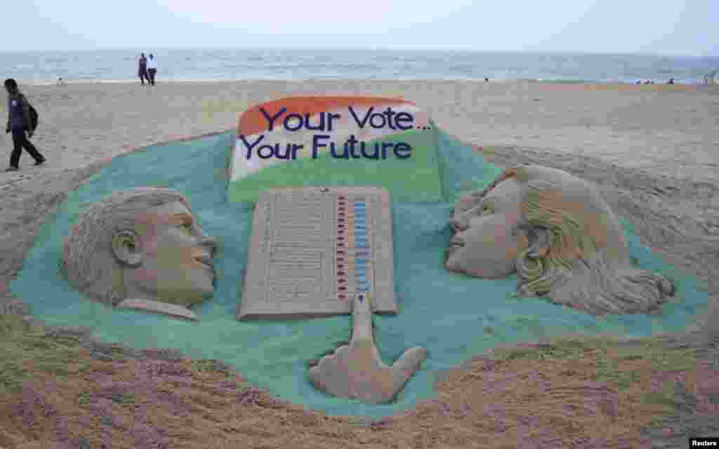 A visitor walks next to a sand sculpture on elections made by Indian sand artist Sudarshan Pattnaik at a beach at Puri in the eastern Indian state of Odisha. Around 815 million people have registered to vote in the world&#39;s biggest election.