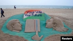 A visitor walks next to a sand sculpture on elections made by Indian sand artist Sudarshan Pattnaik at a beach at Puri in the eastern Indian state of Odisha, April 16, 2014. Around 815 million people have registered to vote in the world's biggest election