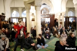 Visitors watch members of the Muslim community praying in the Paris Grand Mosque during an open day weekend for mosques in France, Jan. 10, 2016.