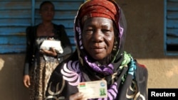 Hauwa Bonkougou, 58 ans, montre sa carte d'électrice dans un bureau de vote de Ouagadougou, le 29 novembre 2015. (REUTERS/Joe Penney)
