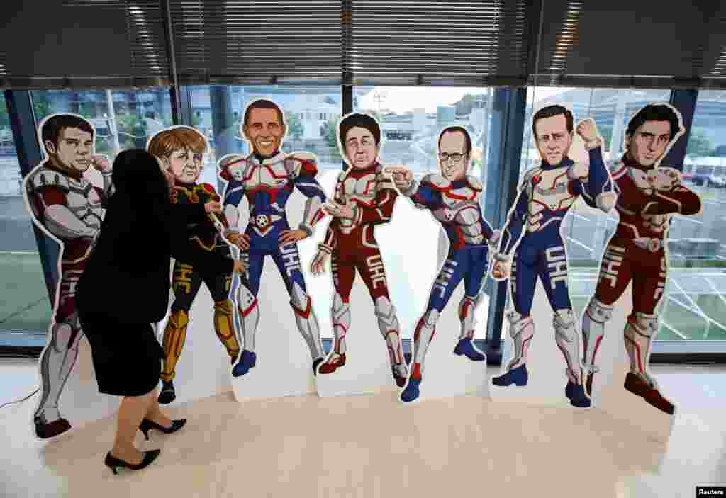 A staff member of the G-7 Network of Health-related NGOs in Japan adjusts cutout panels representing the leaders of the G7 countries as superheroes, at the G-7 NGO center in Ise, Mie Prefecture, Japan.