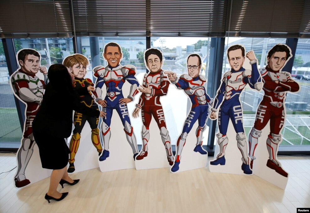 A staff member of the G7 Network of Health-related NGOs in Japan adjusts positions of cutout panels presenting the leaders of the G7 countries as superheroes at the G7 NGO center in Ise, Mie Prefecture, Japan.