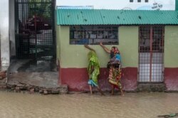 Warga berjalan di dekat rumah yang di sekelilingnya digenangi banjir menjelang topan Amphan, di Dacope, Distrik Khulna, 20 Mei 2020.