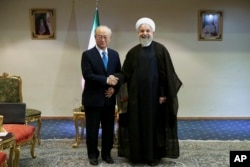 Iran's President Hassan Rouhani, right, shakes hands with the International Atomic Energy Agency's director-general, Yukiya Amano, as they pose for photos at the start of their meeting in Tehran, July 2, 2015.