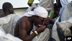 Des migrants mangent un repas chaud après avoir été secouru par le bateau 'Aquarius' le 25 juin 2016