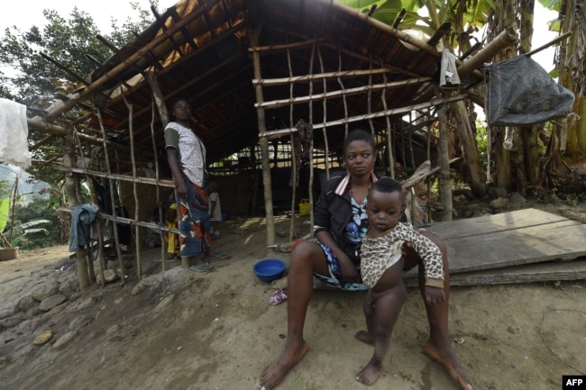 FILE - A Cameroonian refugee sit holding her child in front of a make-shift home, where hundreds are being sheltered, at Bashu-Okpambe village in Boki district of Cross Rivers State in southeast Nigeria, Jan 31, 2018.