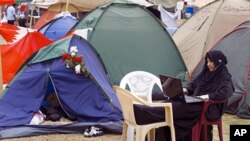 An anti-government Bahraini protester listens to religious programming on the internet outside her tent at Pearl Square in Manama (February 2011 file photo)