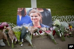 An image and floral tributes for Jo Cox, the 41-year-old British Member of Parliament shot to death yesterday in northern England, lie placed on Parliament Square outside the House of Parliament in London, June 17, 2016.