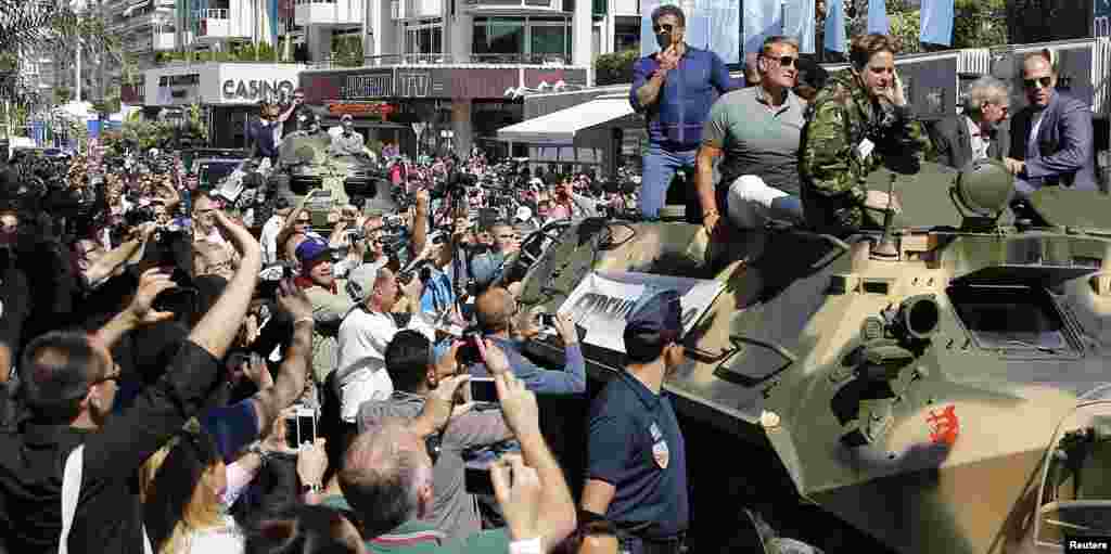 Cast members Sylvester Stallone (L), Dolph Lundgren (2ndL), Harrison Ford (2ndR) and Jason Statham pose on a tank as they arrive on the Croisette to promote the film &quot;The Expendables 3&quot; during the 67th Cannes Film Festival in Cannes.