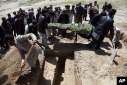 Afghan men bury a victim of Sunday's suicide attack at a voter registration center in Kabul, Afghanistan, April 23, 2018.